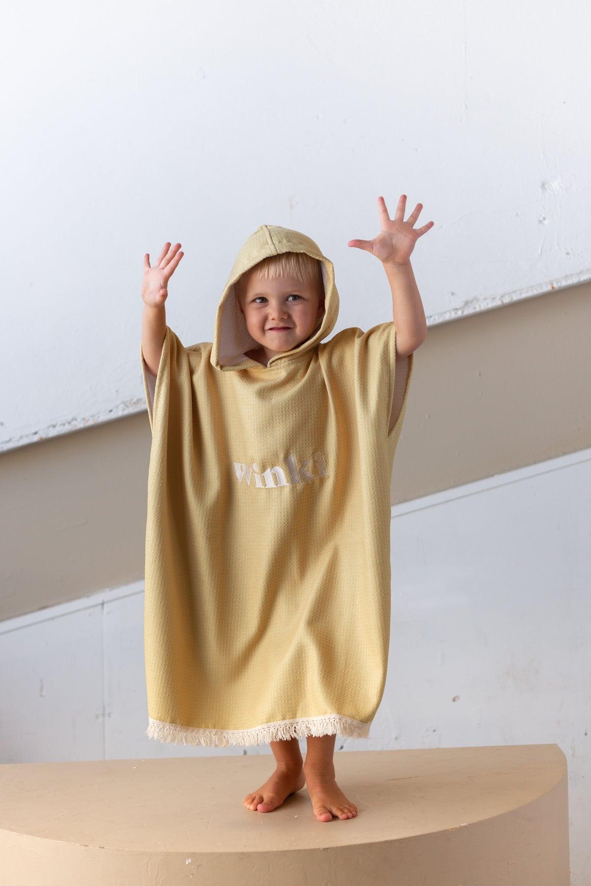 Child in mustard towel outdoors
