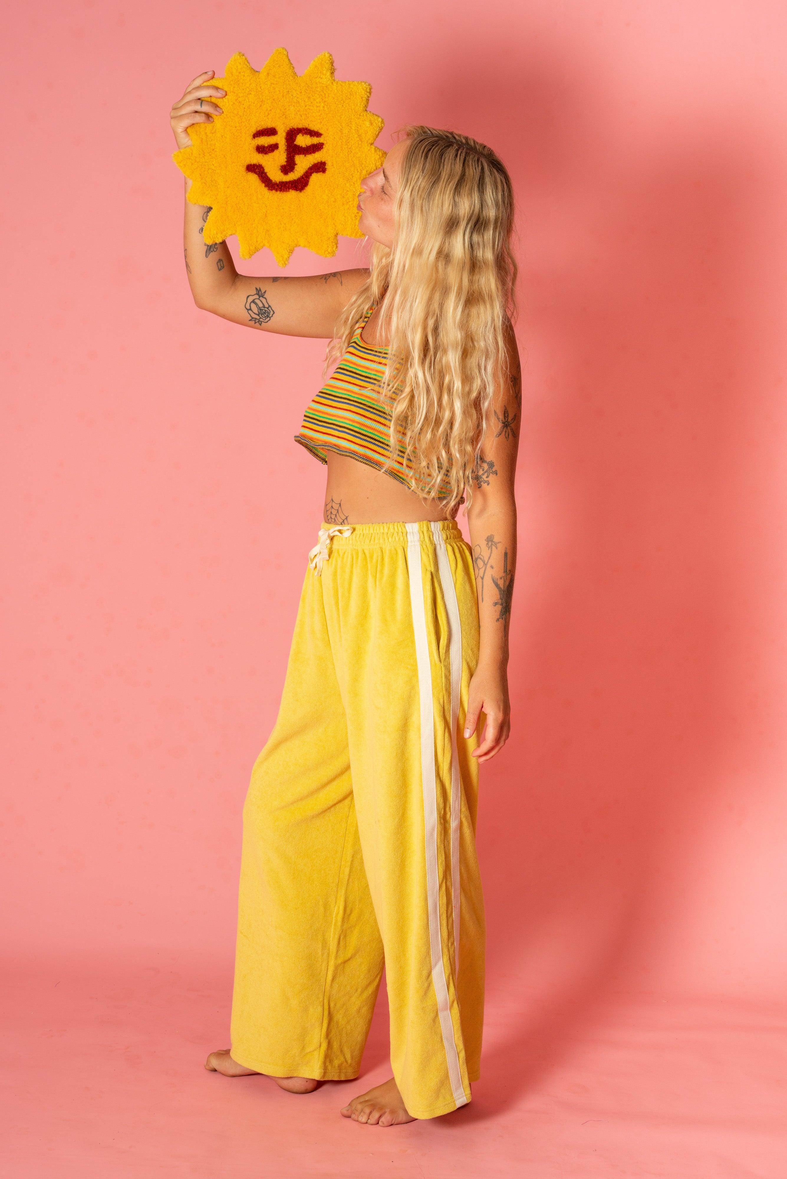 Model holding sun rug in yellow pants