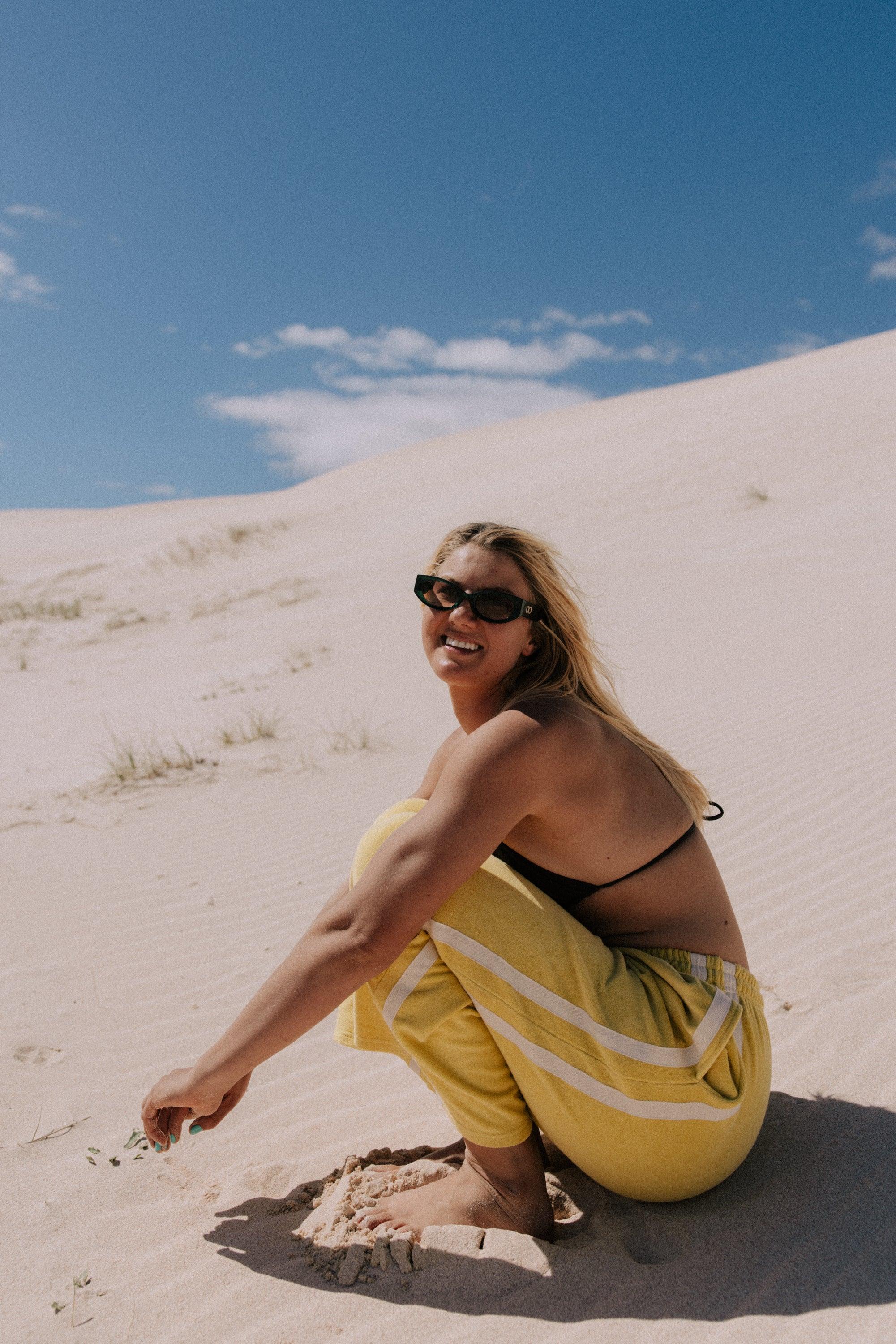 Model in yellow pants on sand