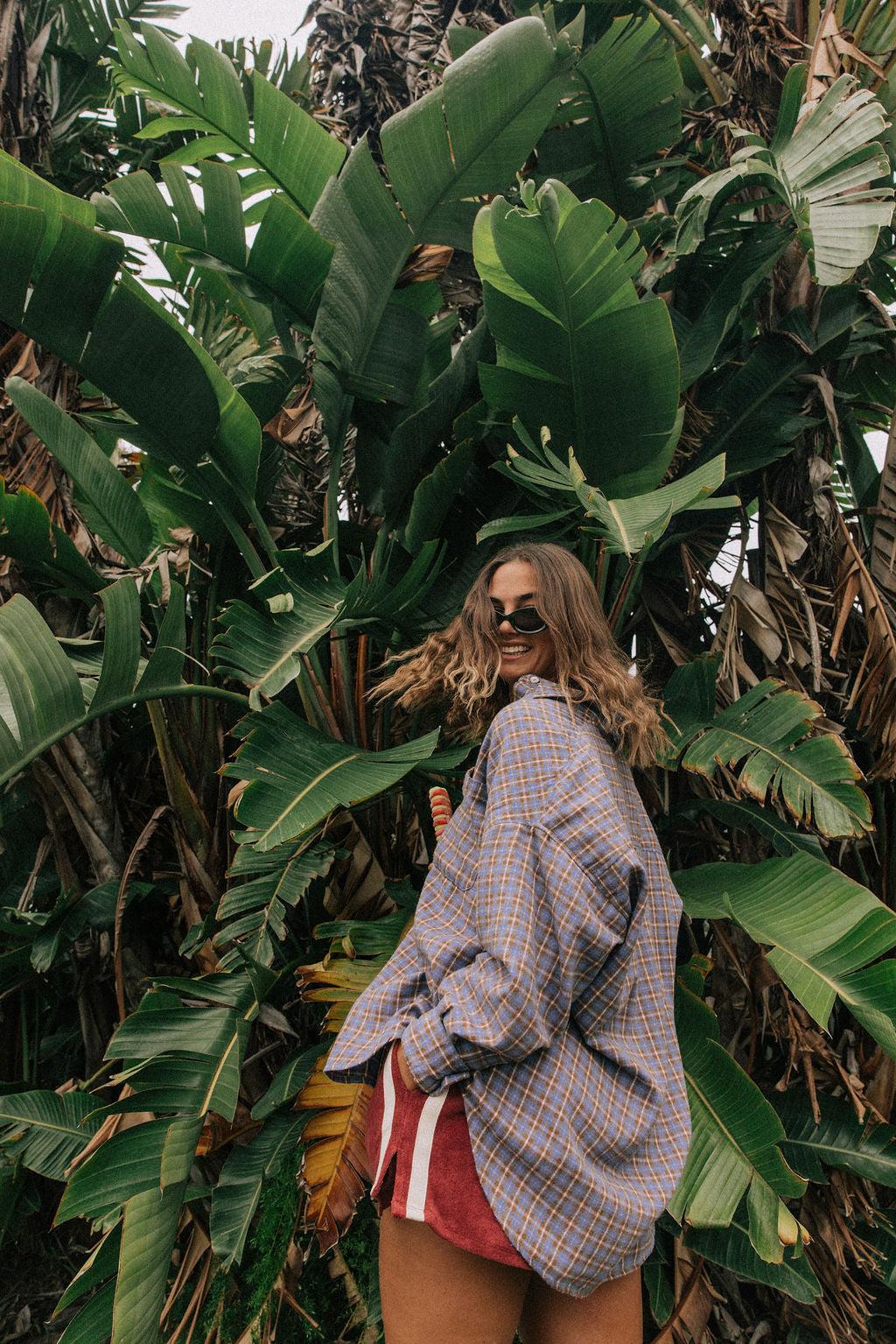 Model in flannel shirt by palm trees