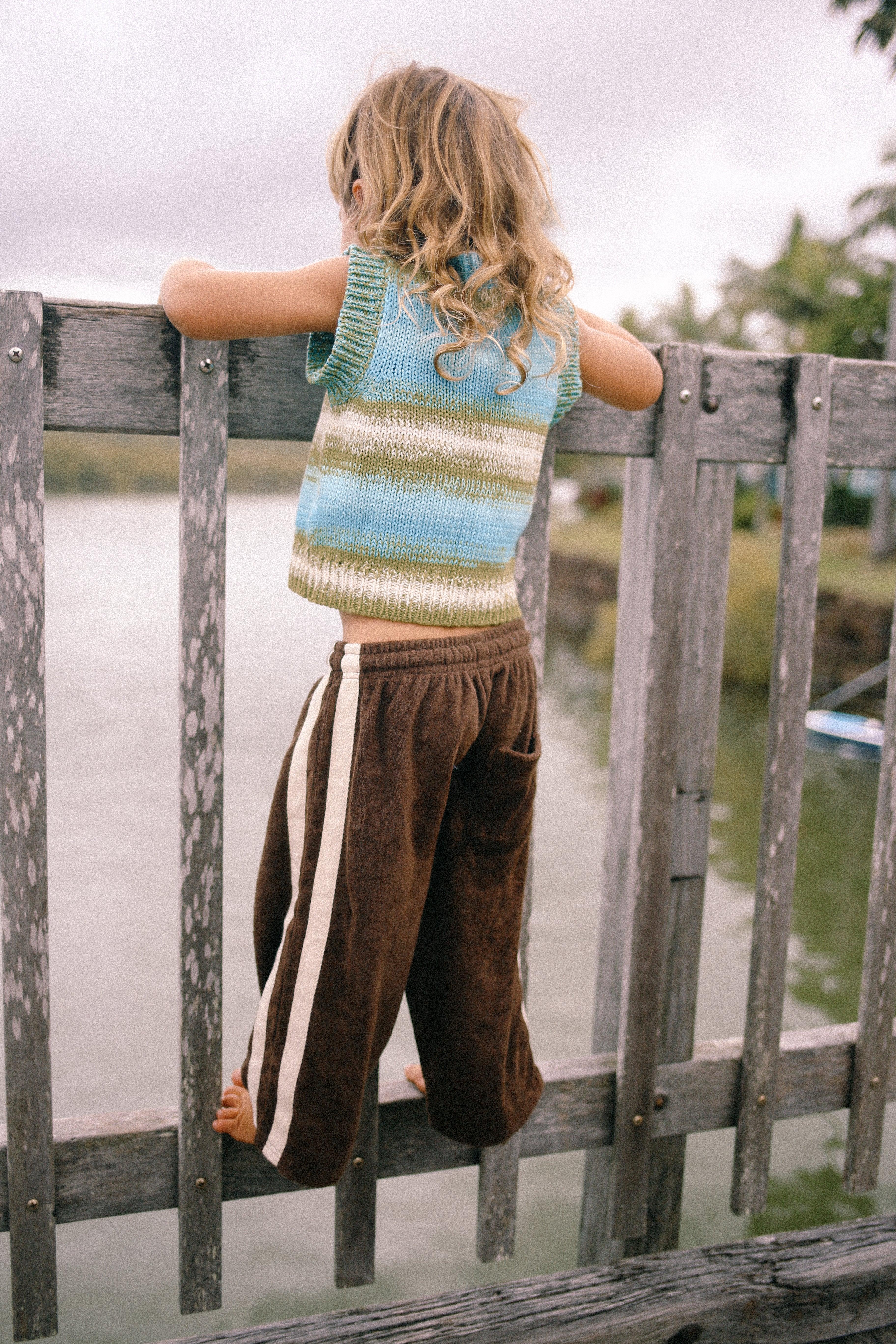 Child climbing fence in vest