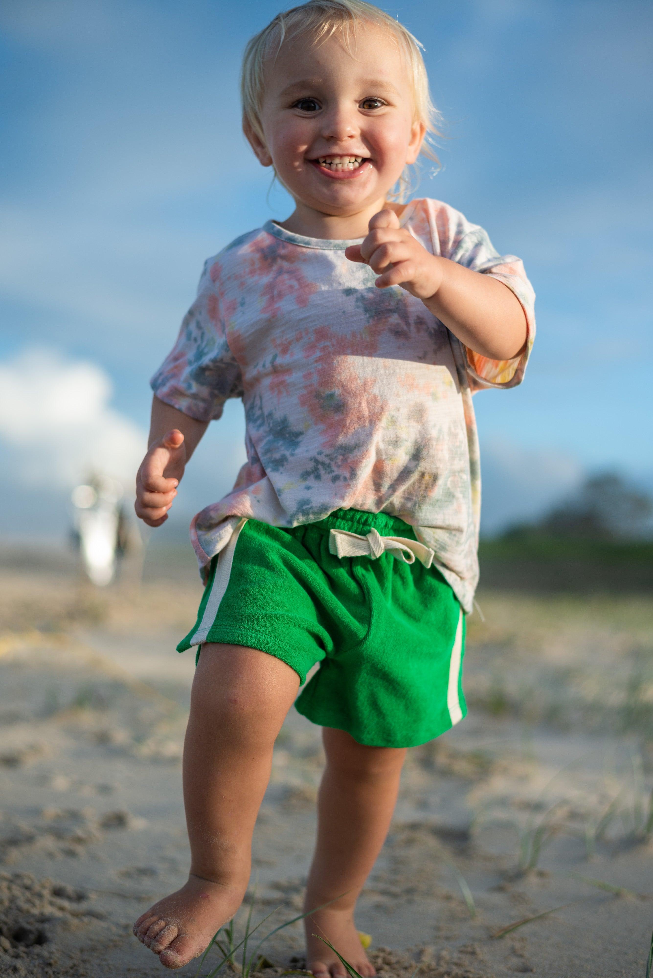 Child in green shorts smiling