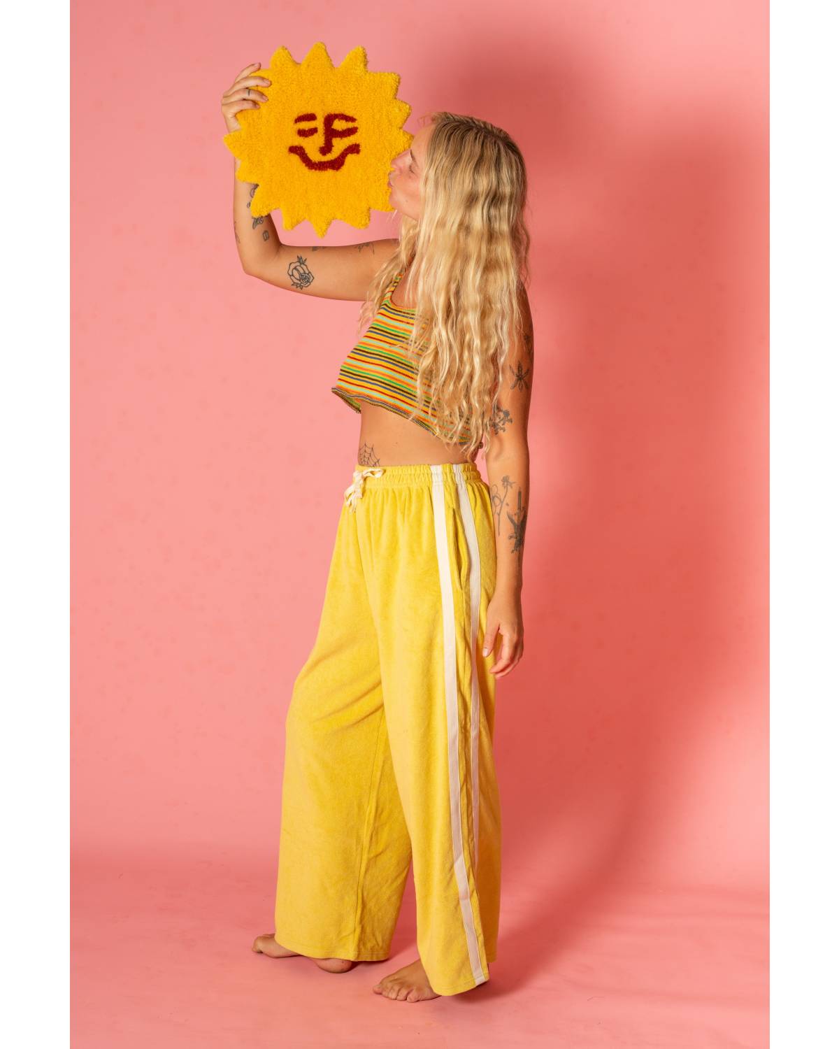 Model holding sun rug in yellow pants