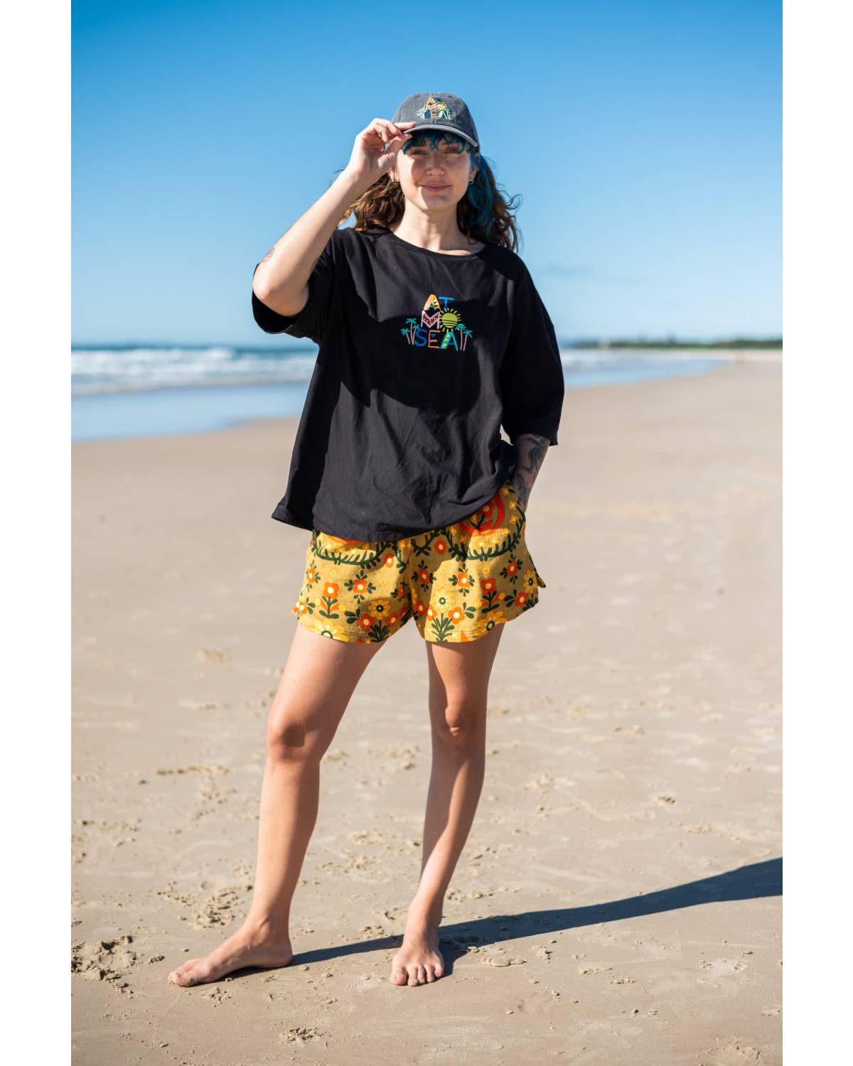Fun Tee on beach, hand on cap