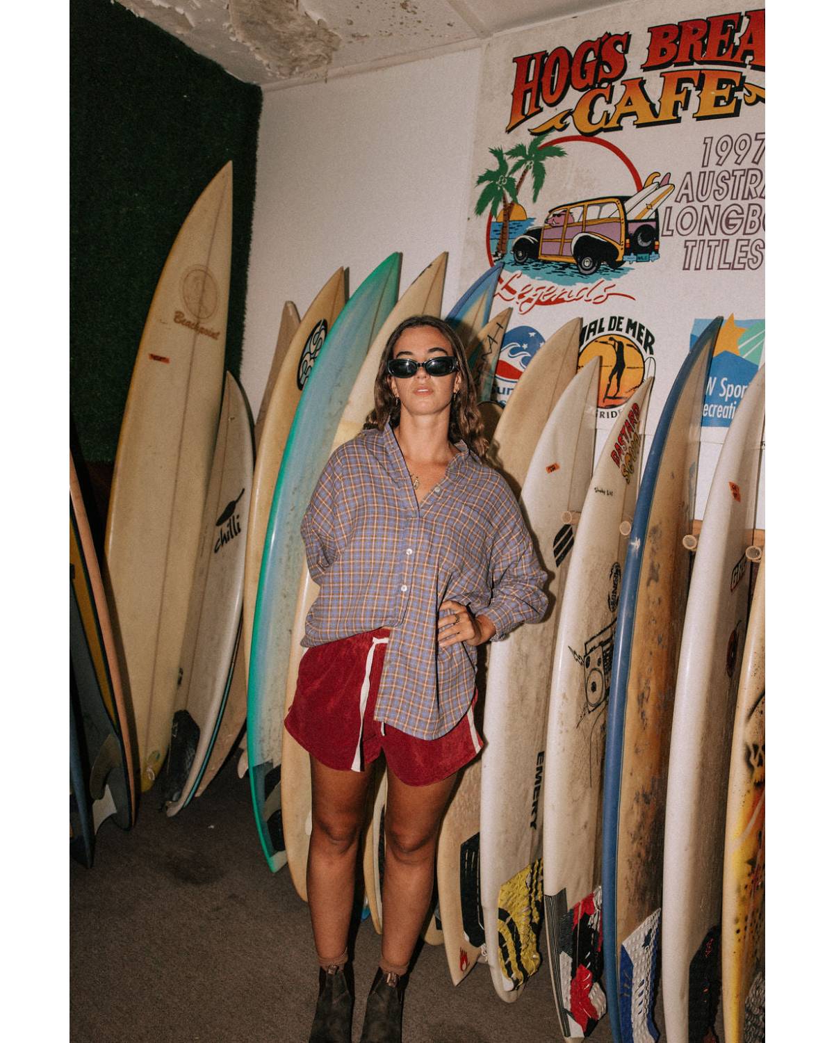 Model in flannel shirt with surfboards