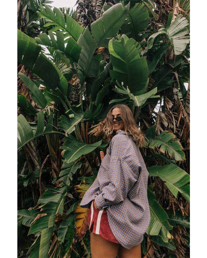 Model in flannel shirt by palm trees