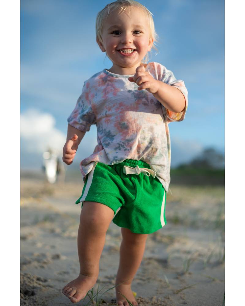 Child in green shorts smiling